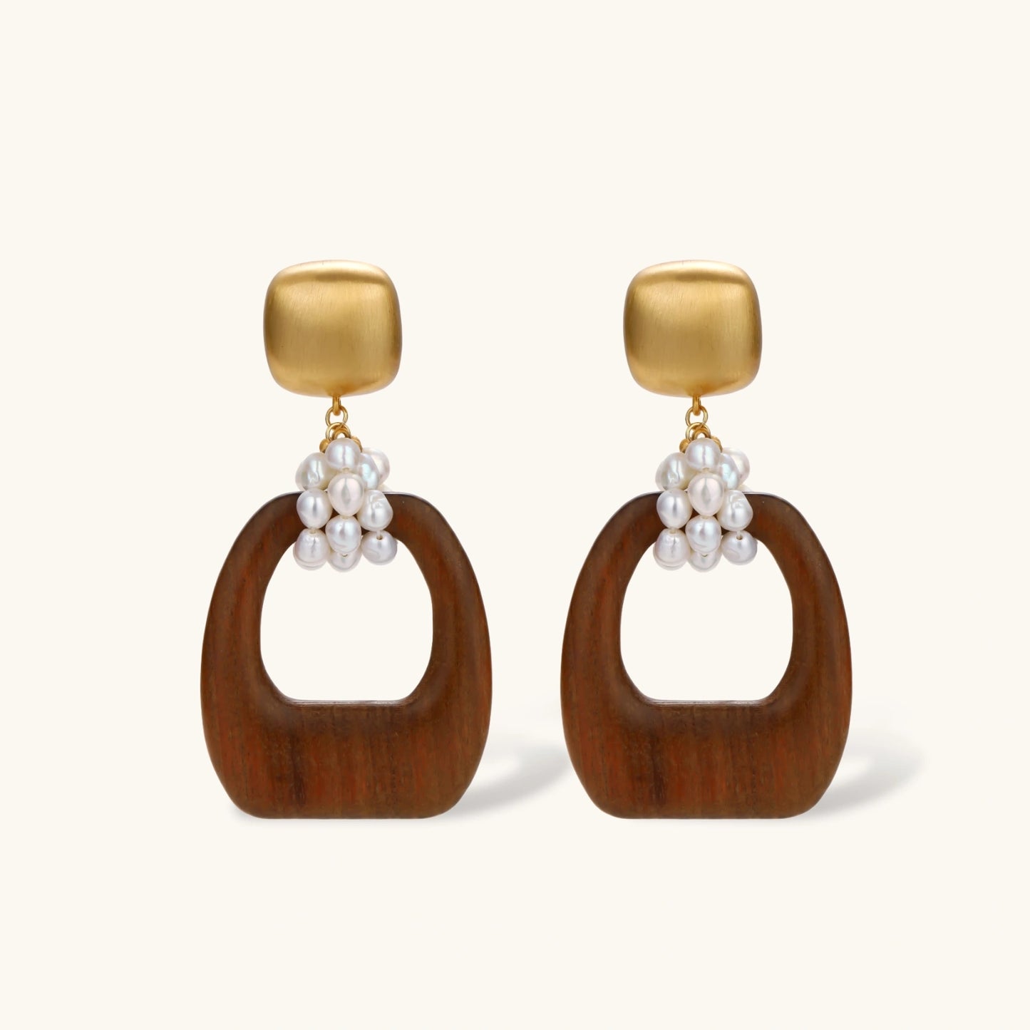 Gold-plated stud earrings with pearl clusters and organic brown wooden hoops on cream background