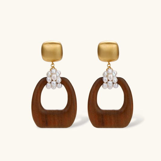 Gold-plated stud earrings with pearl clusters and organic brown wooden hoops on cream background